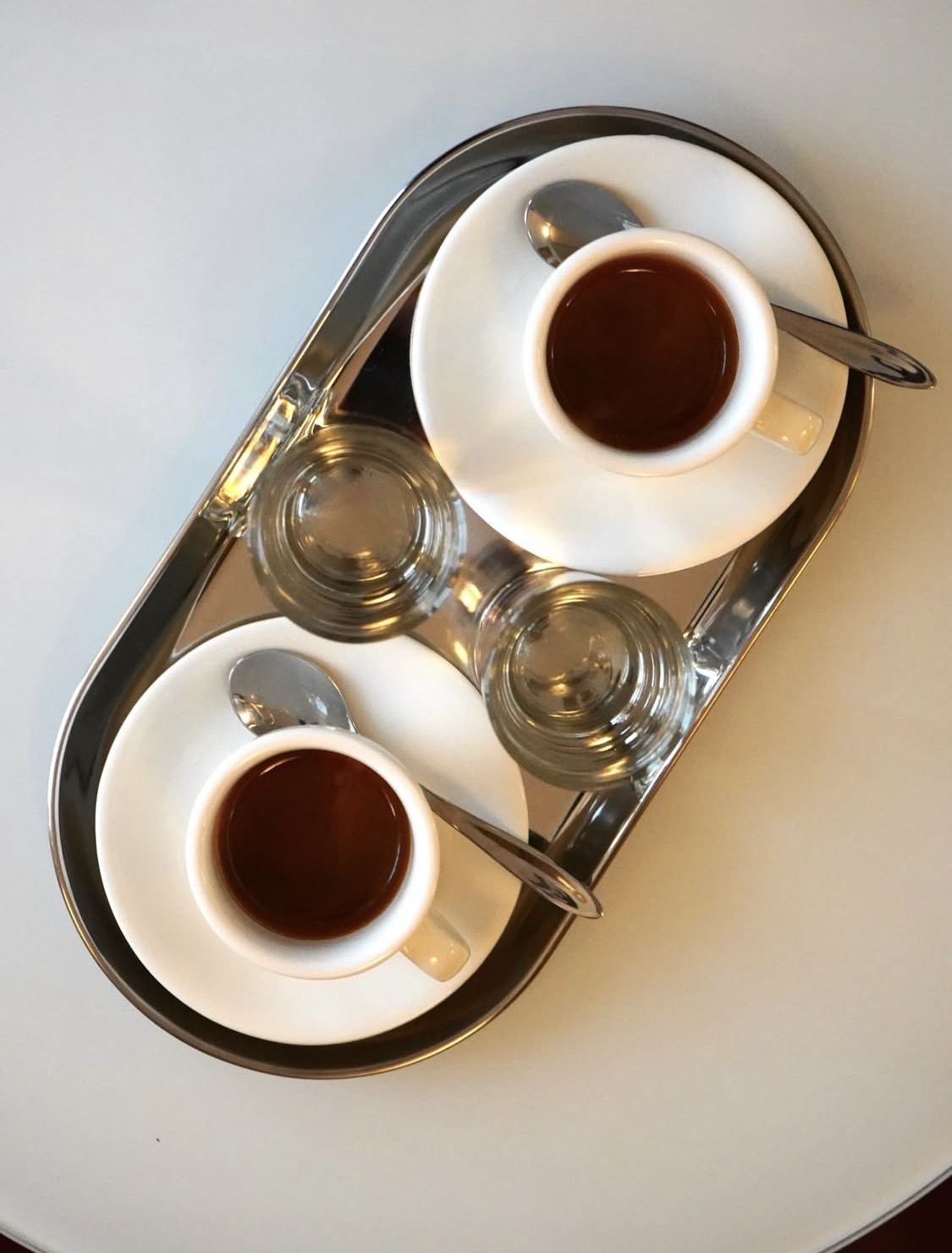 Due tazzine di espresso e bicchieri su un vassoio in acciaio lucido da Bar Tatti, un intimo caf&eacute; bar italiano nel centro di Copenaghen.